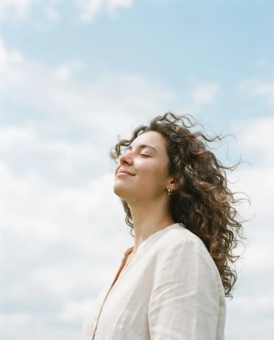 Mujer con los ojos cerrados bajo un cielo azul